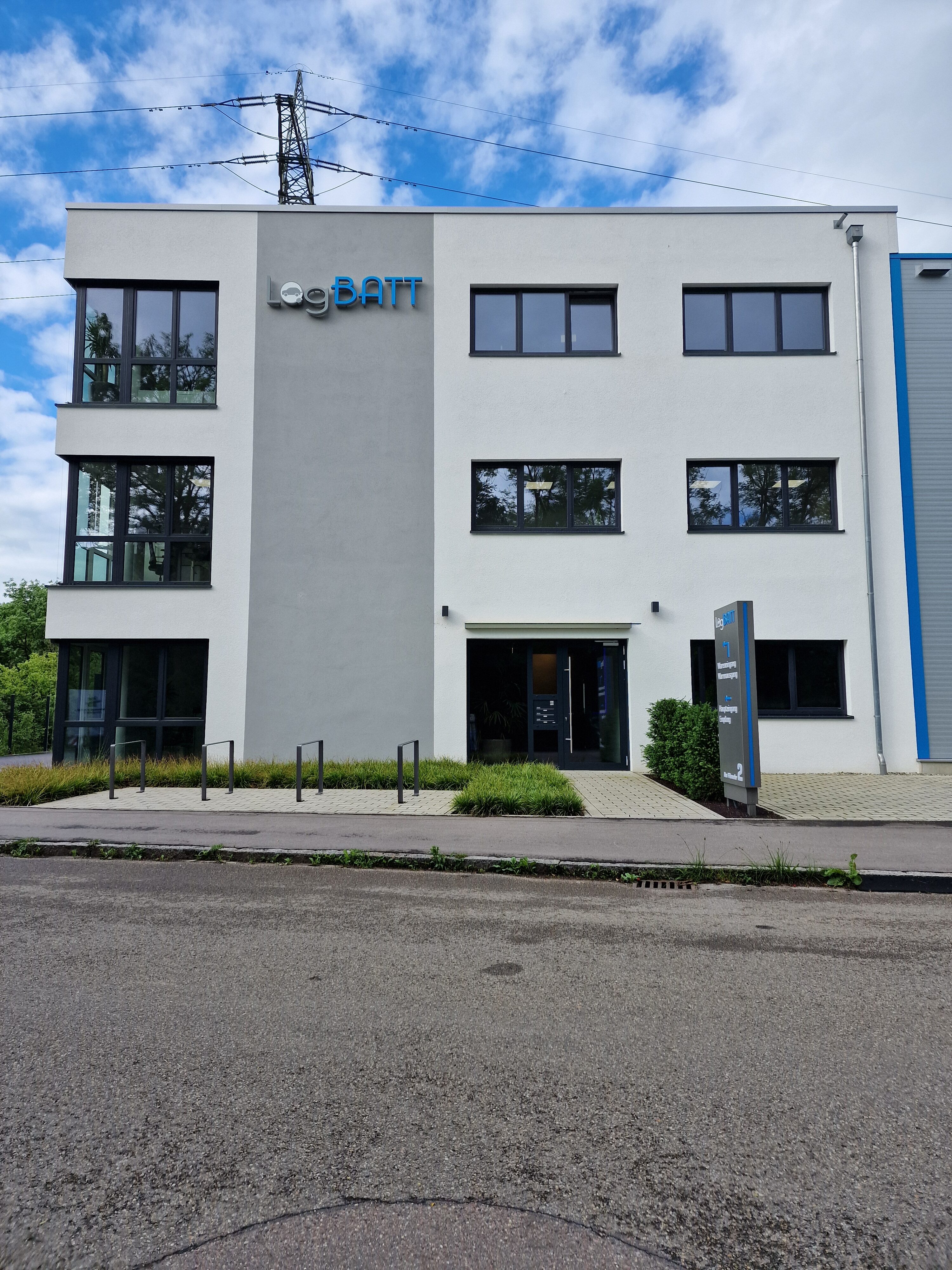Un moderno edificio adibito a uffici con facciata bianca e ampie finestre in una giornata nuvolosa.
